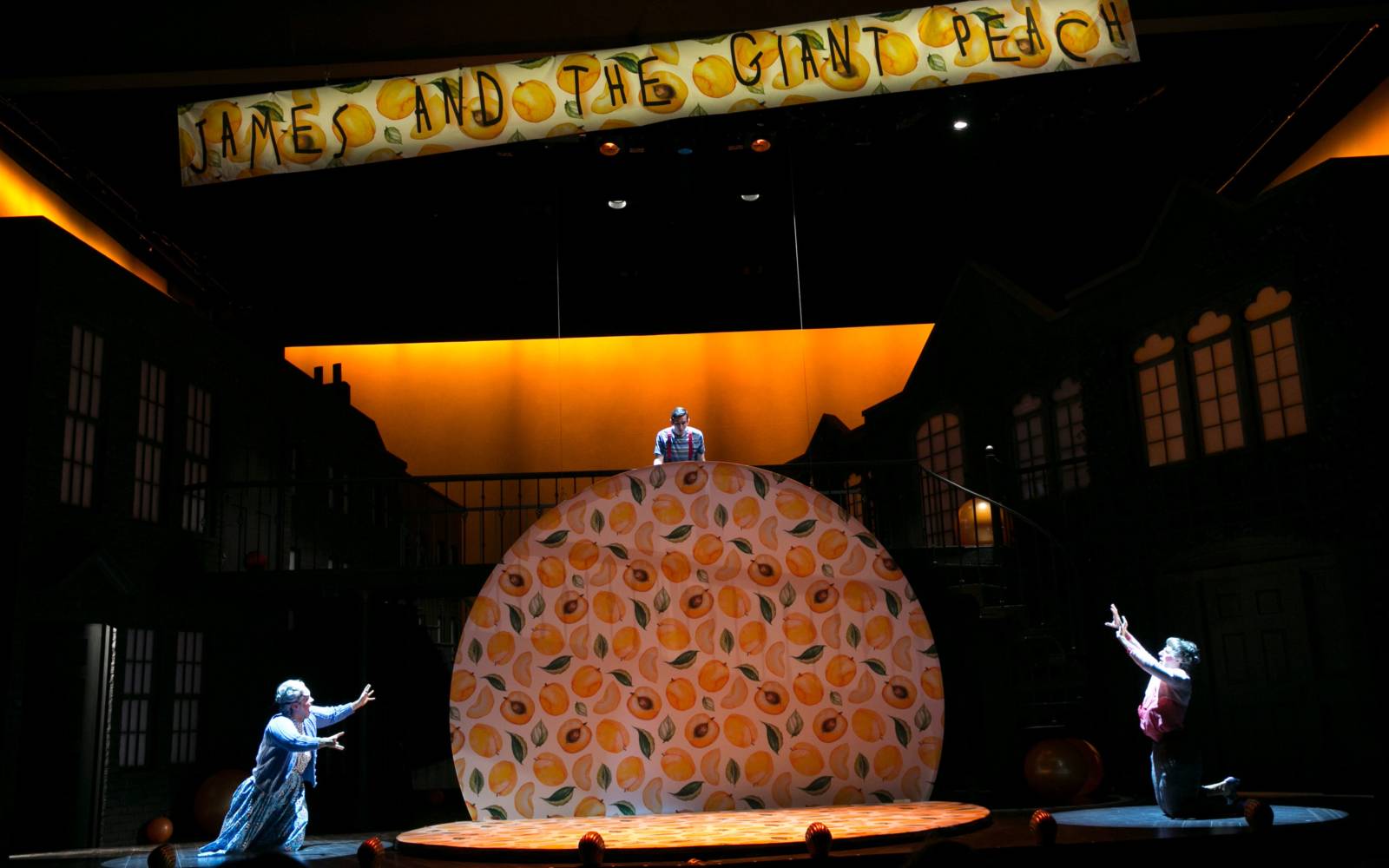 James and the Giant Peach ensemble on stage watch a giant peach rise up from the stage.
